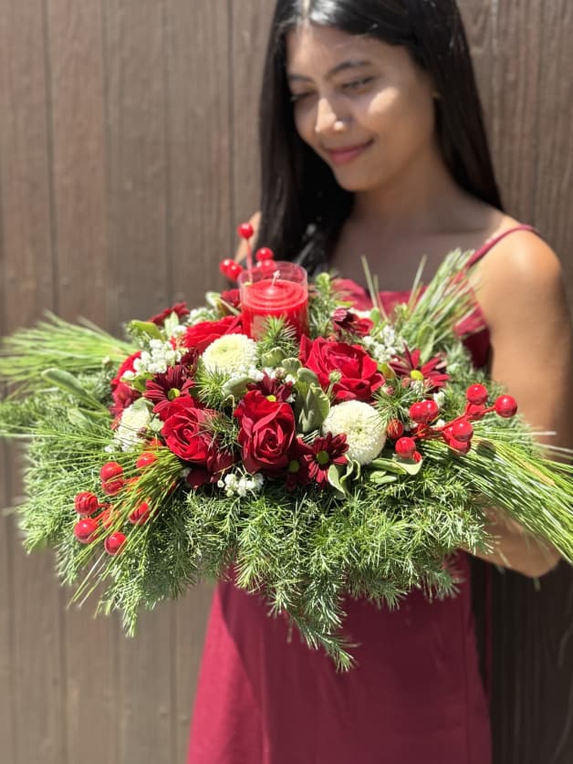A beautiful festive Christmas centrepiece with seasonal greens and red blooms