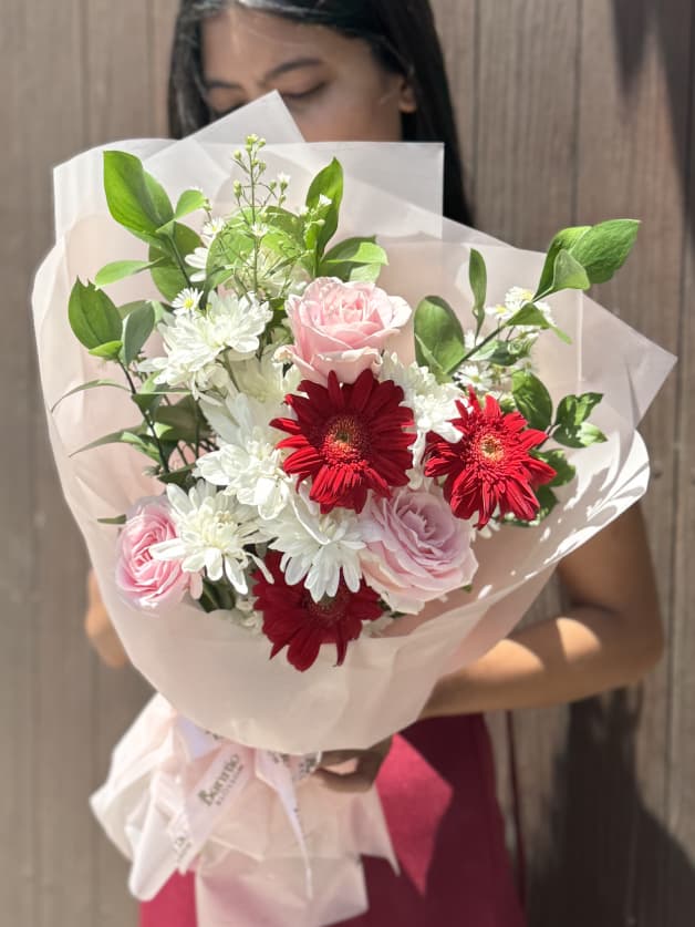 A charming bouquet of red gerberas, pink roses, and white chrysanthemums